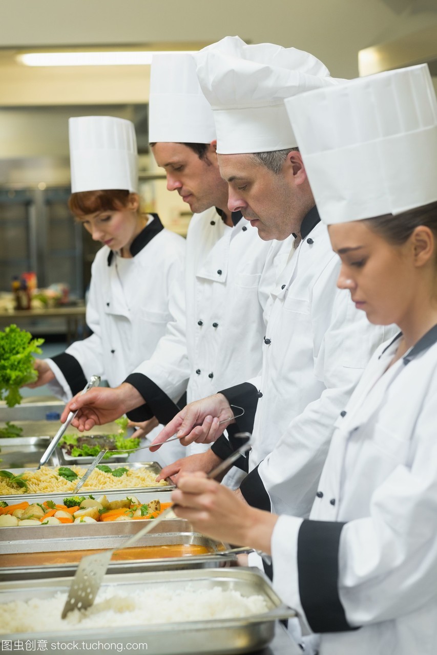 四個廚師在忙碌的廚房里服務(wù)托盤